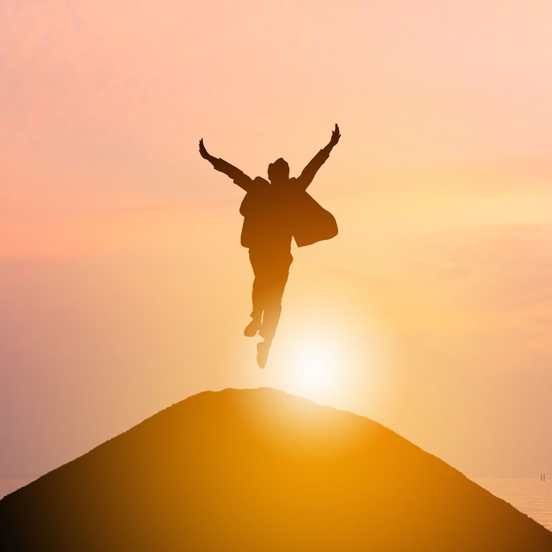 Man jumping on a hill with sunset in background