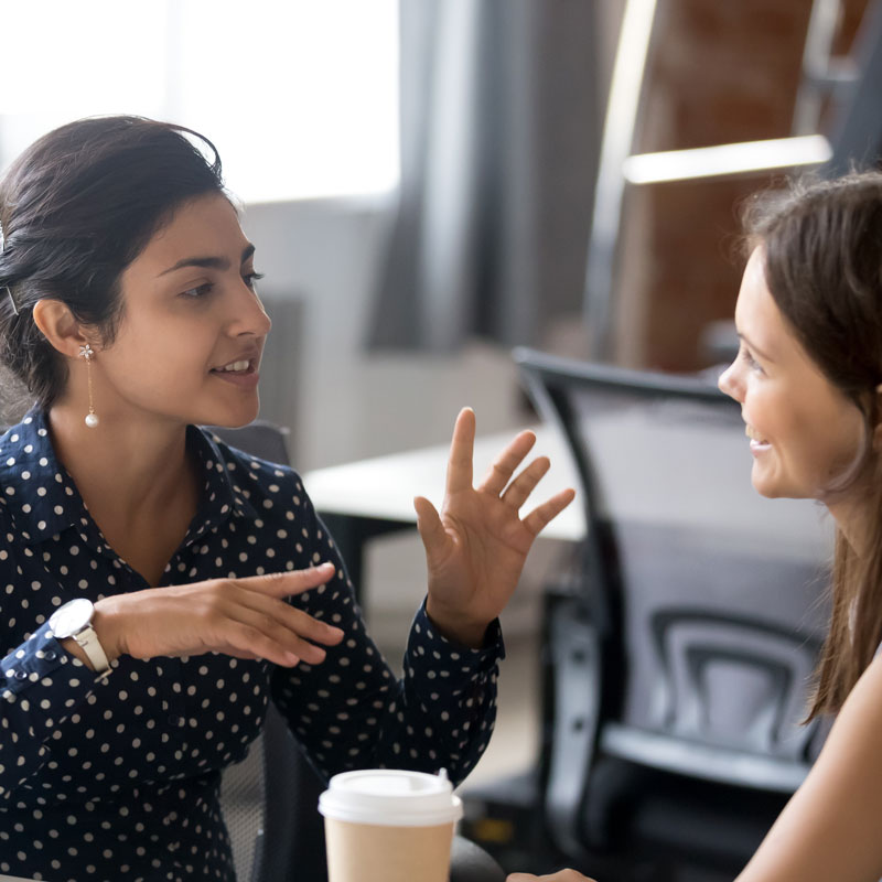 Two women talking and smiling over coffee